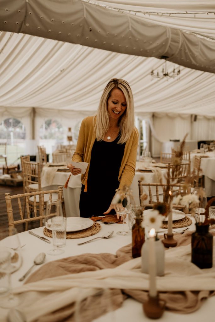 Annabelle styling wedding stationery on a table in a marquee